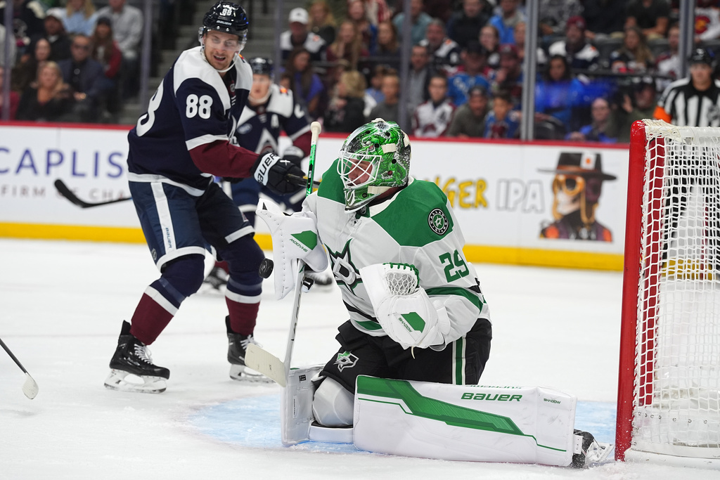 Dallas Stars goaltender Jake Oettinger, front, stops a shot as Colorado Avalanche center Martin Necas covers in the first period of an NHL hockey game Saturday, Oct. 11, 2025, in Denver. (AP Photo/David Zalubowski)