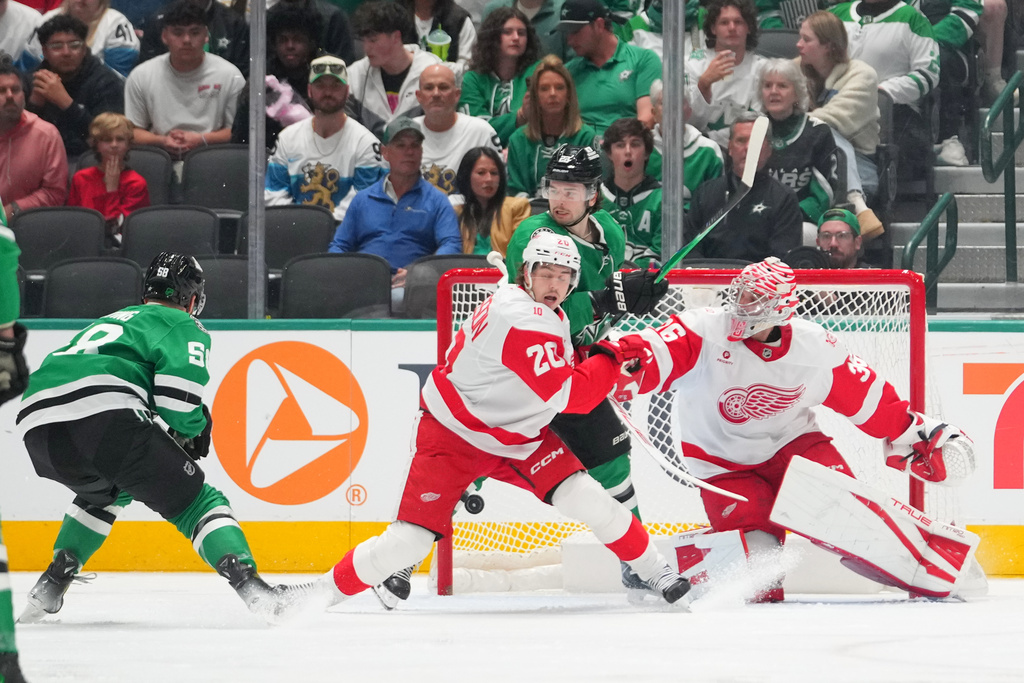 A shot by Dallas Stars left wing Michael Bunting, far left, enters the net of Detroit Red Wings goaltender John Gibson, right, for a goal during the second period of an NHL hockey game Saturday, March 14, 2026, in Dallas. (AP Photo/Julio Cortez)