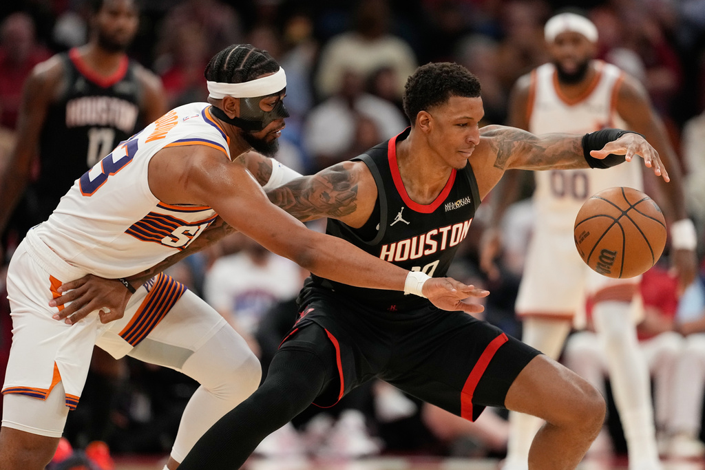 Phoenix Suns' Jordan Goodwin, left, reaches to knock the ball away from Houston Rockets' Jabari Smith Jr. during the first half of an NBA basketball game Monday, Jan. 5, 2026, in Houston. (AP Photo/David J. Phillip)