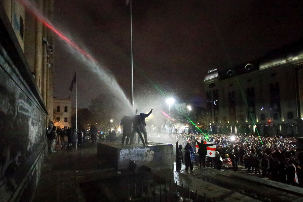 FILE - Demonstrators stand under the spray from a water cannon outside the parliament building in Tbilisi, Georgia, on Dec. 2, 2024, to protest the government's decision to suspend negotiations on joining the European Union. (AP Photo/Zurab Tsertsvadze, File)