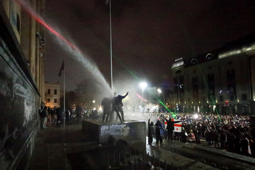 FILE - Demonstrators stand under the spray from a water cannon outside the parliament building in Tbilisi, Georgia, on Dec. 2, 2024, to protest the government's decision to suspend negotiations on joining the European Union. (AP Photo/Zurab Tsertsvadze, File) FILE - Demonstrators stand under the spray from a water cannon outside the parliament building in Tbilisi, Georgia, on Dec. 2, 2024, to protest the government's decision to suspend negotiations on joining the European Union. (AP Photo/Zurab Tsertsvadze, File)