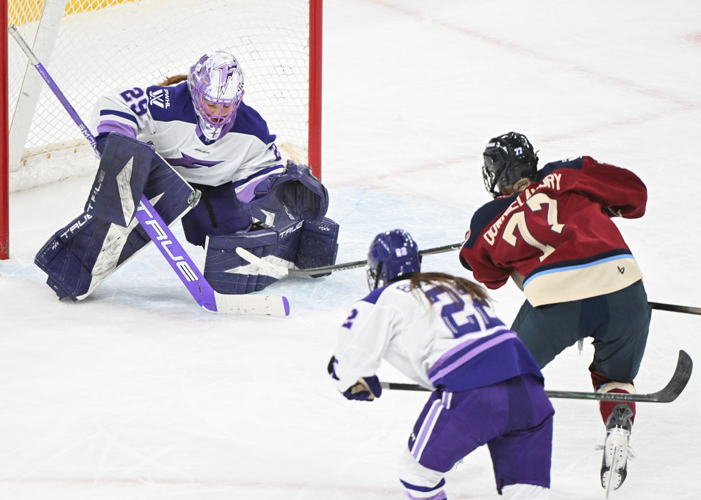 Montreal Victoire's Jade Downie-Landry (77) shoots against Minnesota Frost goaltender Nicole Hensley (29) as Frost's Natalie Buchbinder (22) defends during third-period PWHL hockey game action in Laval, Quebec, Sunday, March 1, 2026. (Graham Hughes/The Canadian Press via AP)
