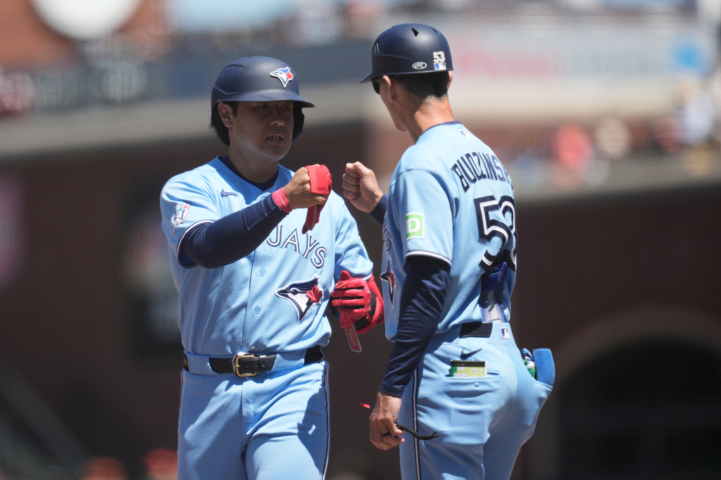 Toronto Blue Jays' Kazuma Okamoto, left, is congratulated by first base coach Mark Budzinski after hitting a single during the eighth inning of a baseball game against the San Francisco Giants Wednesday, July 8, 2026, in San Francisco. (AP Photo/Jeff Chiu)