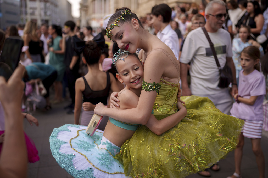 Daria Toma, 15, right, and Dora, 10, of the Romanian National Opera's Ballet Studio, hug outside the National History Museum of Romania during Dance Night, an event featuring a wide variety of dance styles performed on the Calea Victoriei avenue in Bucharest, Romania, Saturday, Aug. 23, 2025. (AP Photo/Andreea Alexandru)