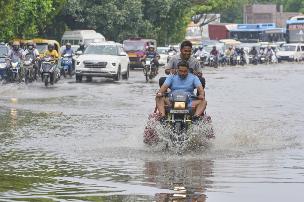 Commuters wade through the flooded water on a road after the river Yamuna, swollen by incessant rain in the higher regions, overran its banks, in New Delhi, India, Friday, Sept. 5, 2025. (AP Photo/Manish Swarup)