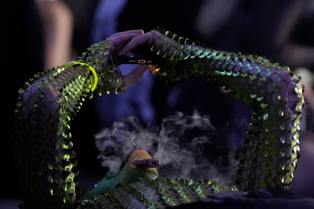 A man lying down, vapes while looking at his phone during a Halloween rave in Kyiv, Ukraine, Saturday, Oct. 25, 2025. (AP Photo/Julia Demaree Nikhinson)