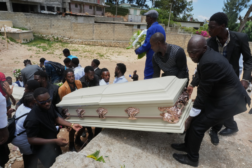 Relatives lift the coffin of a gang attack victim for burial at the cemetery after the funeral ceremony for four people killed during the attack in the Kenscoff neighborhood of Port-au-Prince, Haiti, Sunday, Aug. 30, 2026. (AP Photo/Odelyn Joseph)