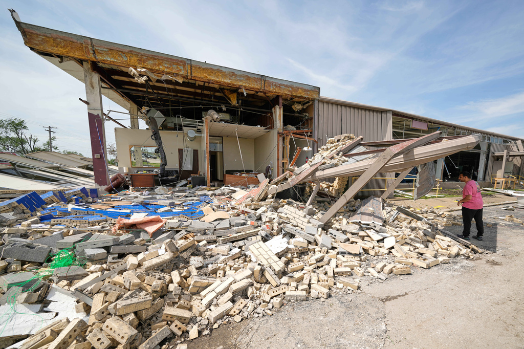 A man looks though debris Tuesday, April 14, 2026, at a pipe manufacturing facility that was damaged by a tornado Monday in Ottawa, Kan. (AP Photo/Charlie Riedel)