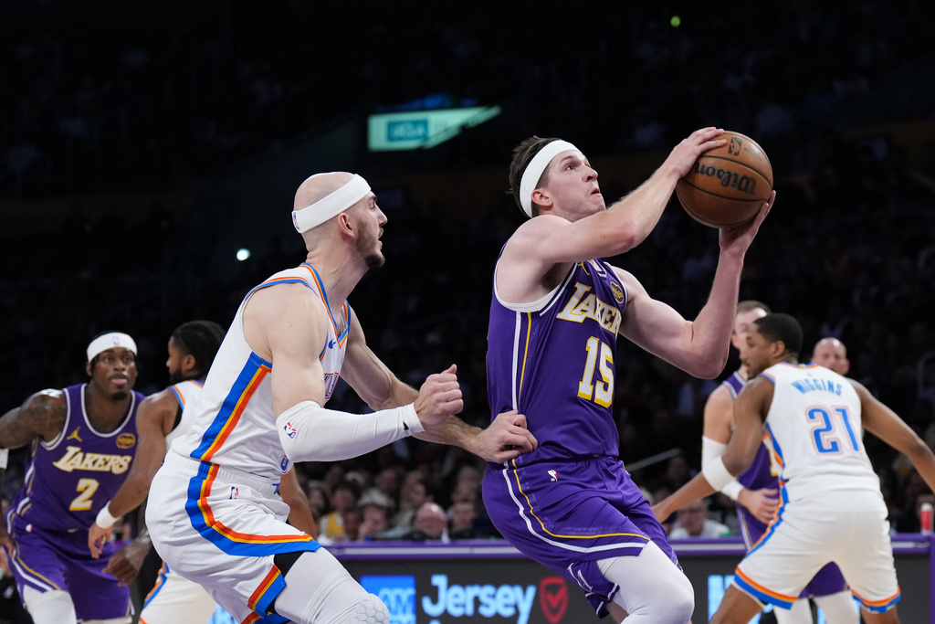 Los Angeles Lakers guard Austin Reaves (15) drives to the basket past Oklahoma City Thunder guard Alex Caruso during the first half of an NBA basketball game Monday, Feb. 9, 2026, in Los Angeles. (AP Photo/Jae C. Hong)