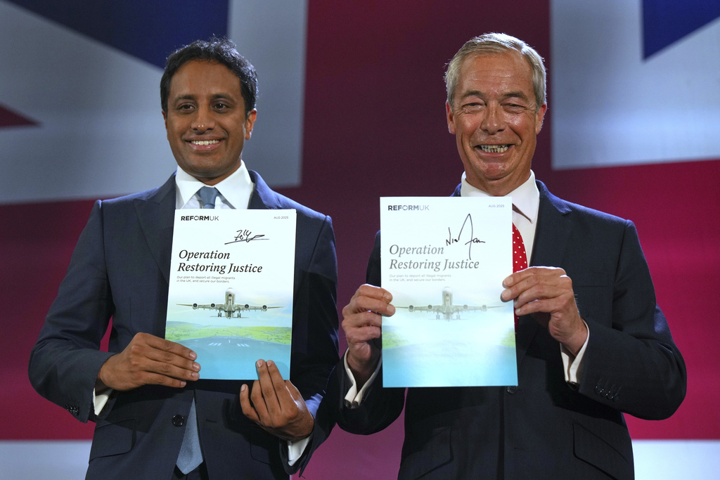British Reform party leader Nigel Farage and Zia Yusuf, left, show the program Operation Restoring Justice during a press conference in a hangar at Oxford Airport in Kidlington, England, Tuesday, Aug. 26, 2025.(AP Photo/Joanna Chan)