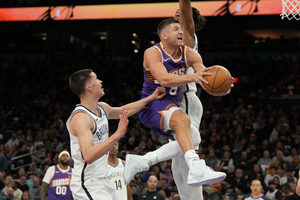 Phoenix Suns guard Grayson Allen (8) drives between Brooklyn Nets guard Egor Demin, left, and center Nic Claxton during the second half of an NBA basketball game, Tuesday, Jan. 27, 2026, in Phoenix. (AP Photo/Rick Scuteri)
