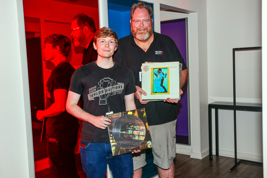This photo provided by Mel D. Cole shows Carson Bispels, left, posing for a photo with his father, Martin Bispels, who recently started Retroactv, a company that sells rock merchandise dating back to the 1960s and 1970s, on Aug. 1, 2025, in Asbury Park, N.J. (Mel D. Cole via AP)