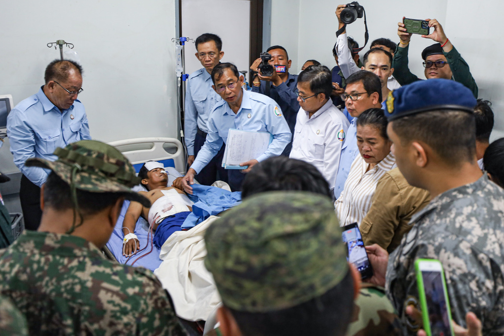 In this photo released by Agence Kampuchea Press (AKP), an injured man, rear center, is visited by members of the ASEAN's observer team (AOT) in a hospital in Prey Chan, a border village to Thailand, in Banteay Meanchey province, Cambodia, Thursday, Nov. 13, 2025. (AKP via AP)