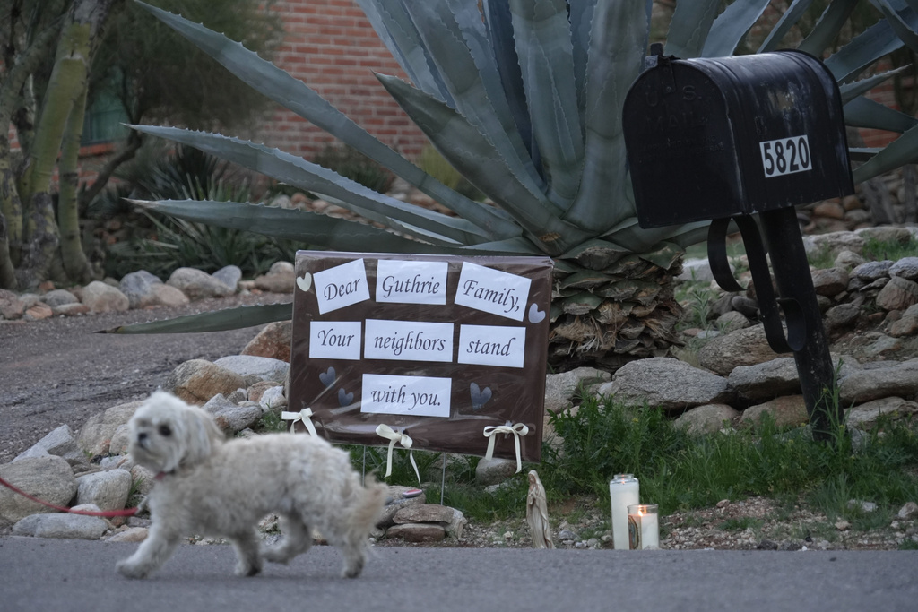 Lit candles next to a sign from neighbors supporting the Guthrie family outside of Nancy Guthrie’s house in the early morning hours of Sunday, Feb. 8, 2026 in Tucson, Ariz. (AP Photo/Ty ONeil)