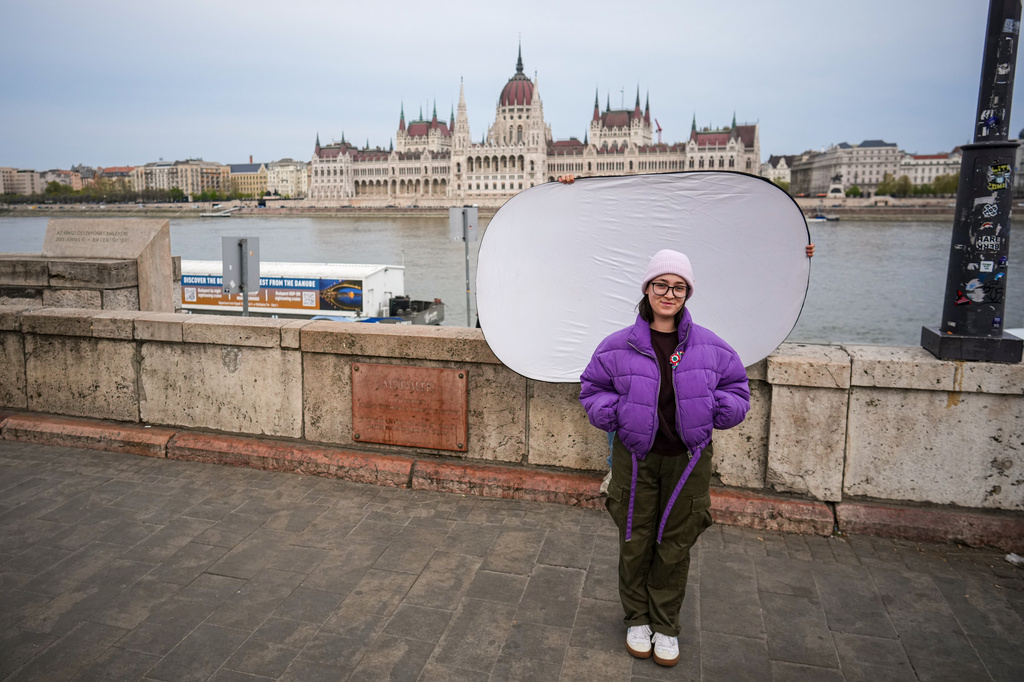 Eszter Kulisek M., 24, poses for a portrait backdropped by Parliament in Budapest, Hungary, Monday, April 13, 2026. "I hope that young people will start participating in society; that they'll be more active in politics, that they'll take on our everyday challenges." (AP Photo/Petr David Josek)