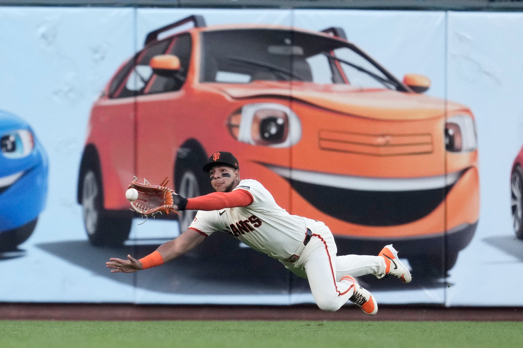 San Francisco Giants left fielder Victor Bericoto dives to catch a fly out hit by Colorado Rockies' Cole Carrigg during the first inning of a baseball game Thursday, July 9, 2026, in San Francisco. (AP Photo/Jeff Chiu)