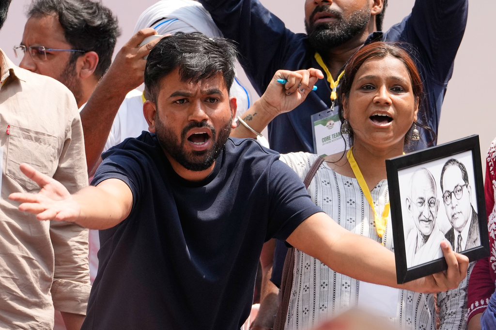 Abhijeet Dipke, center, founder of the Cockroach Janta Party gestures as he holds the photograph of Mahatma Gandhi and Bhim Rao Ambedkar during a protest demanding the resignation of Education Minister Dharmendra Pradhan over alleged examination irregularities and repeated paper leaks in New Delhi, India, Saturday, June 20, 2026. (AP Photo/Manish Swarup)