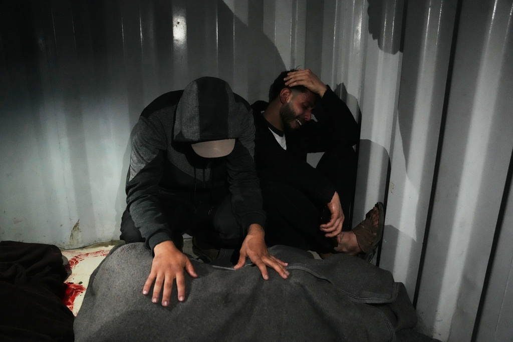 Palestinians mourn over the body of Ahmed Tabasha, a Palestinian policeman killed in an Israeli military strike, during his funeral at Al-Awda Hospital in Nuseirat, southern Gaza Strip, Sunday, March 22, 2026. (AP Photo/Abdel Kareem Hana)