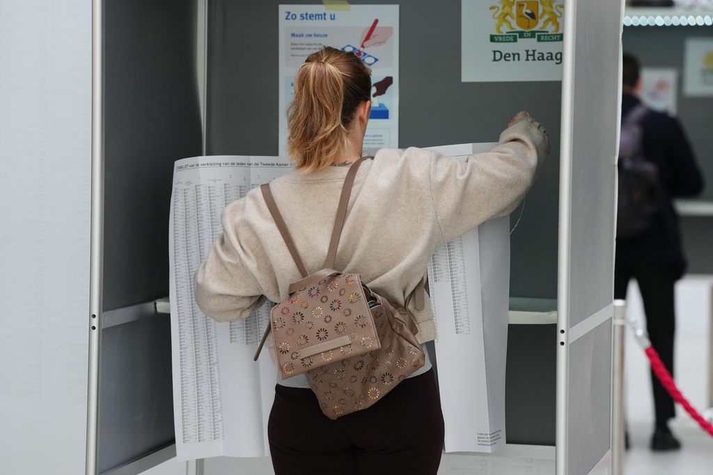 A woman stands at a polling station with a sheet listing all the candidates during general elections in The Hague, Netherlands, Wednesday, Oct. 29, 2025. (AP Photo/Peter Dejong)