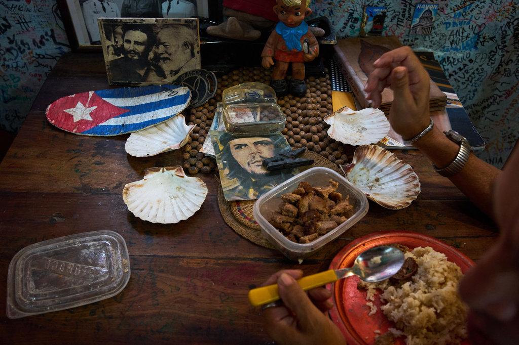A souvenir shop worker eats next to images of Che Guevara, Fidel Castro, and Ernest Hemingway in Havana, Tuesday, June 2, 2026. (AP Photo/Ramon Espinosa)