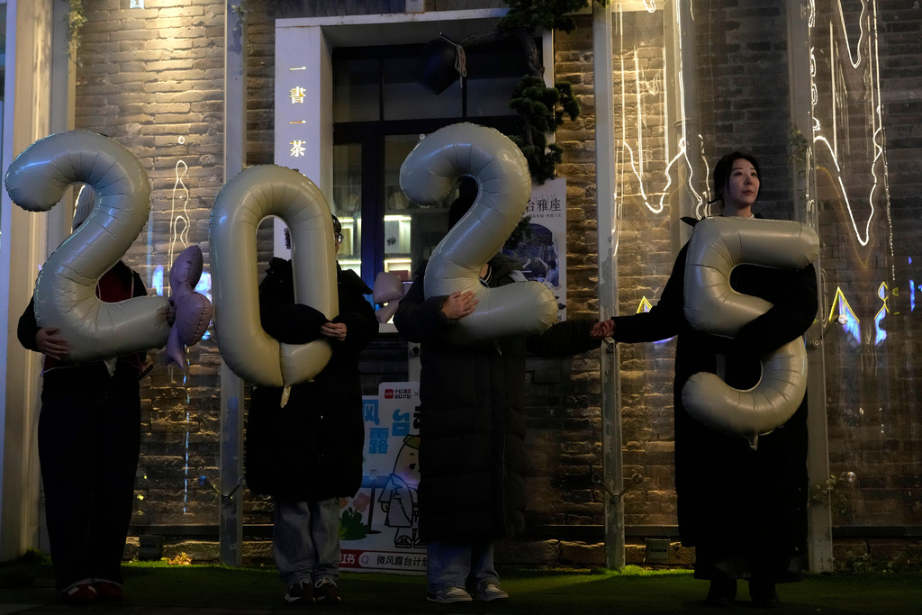 Workers hold up balloons showing 2025 as they shoot a video to welcome 2026 at a shopping district in Beijing, China, Thursday, Dec. 18, 2025. (AP Photo/Ng Han Guan)