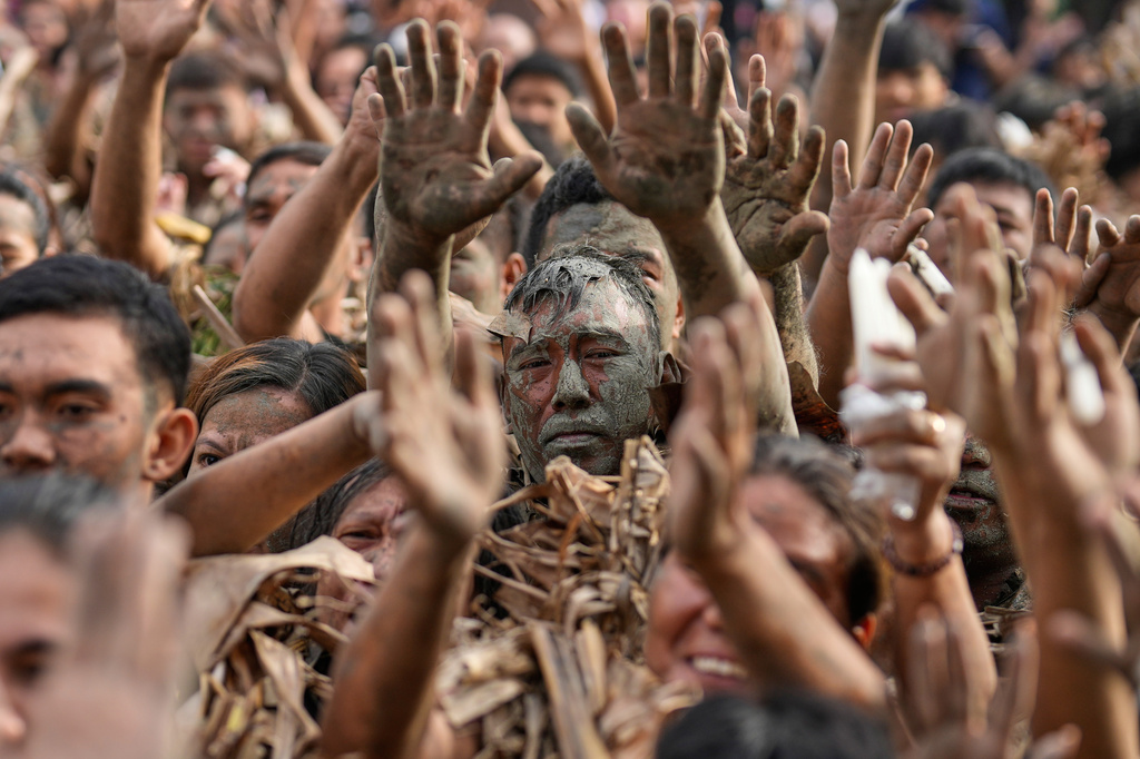 Melencio Neuda, center, and other devotees who participated in the mud people festival raise their hands during a mass on the feast day of Saint John the Baptist at Bibiclat, Nueva Ecija province, northern Philippines, Wednesday, June 24, 2026. (AP Photo/Aaron Favila)