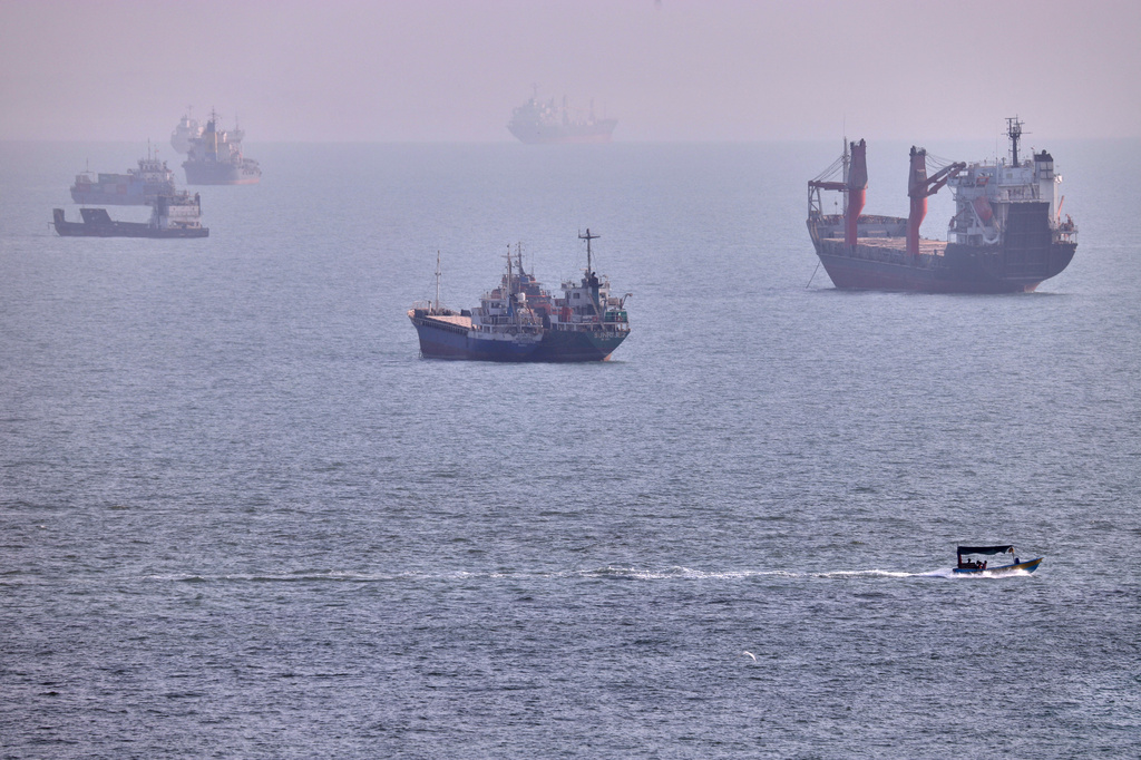 A small boat sails past cargo ships and other commercial vessels anchored in the Strait of Hormuz off Bandar Abbas, Iran, Wednesday, Aug. 5, 2026. (Amirhosein Khorgooi/ISNA via AP)