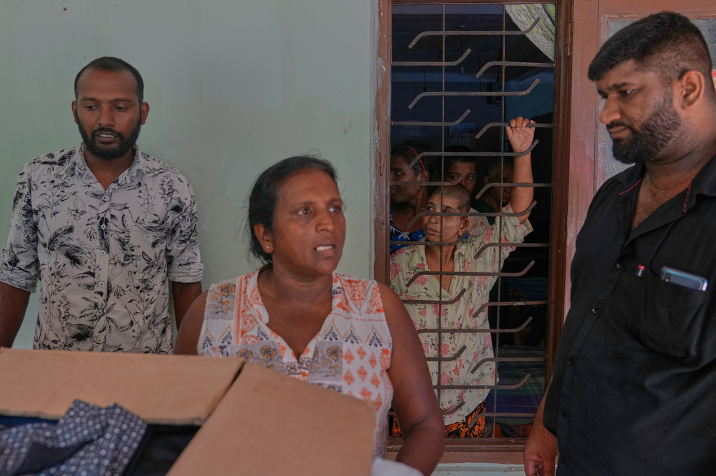 Residents look at donors through an iron grill as they spend the day inside their dormitory at a nursing home, where inmates of another nursing home that caught fire on Wednesday are being temporarily housed in Anguruwatota, Sri Lanka, Friday, June 5, 2026. (AP Photo/Eranga Jayawardena)