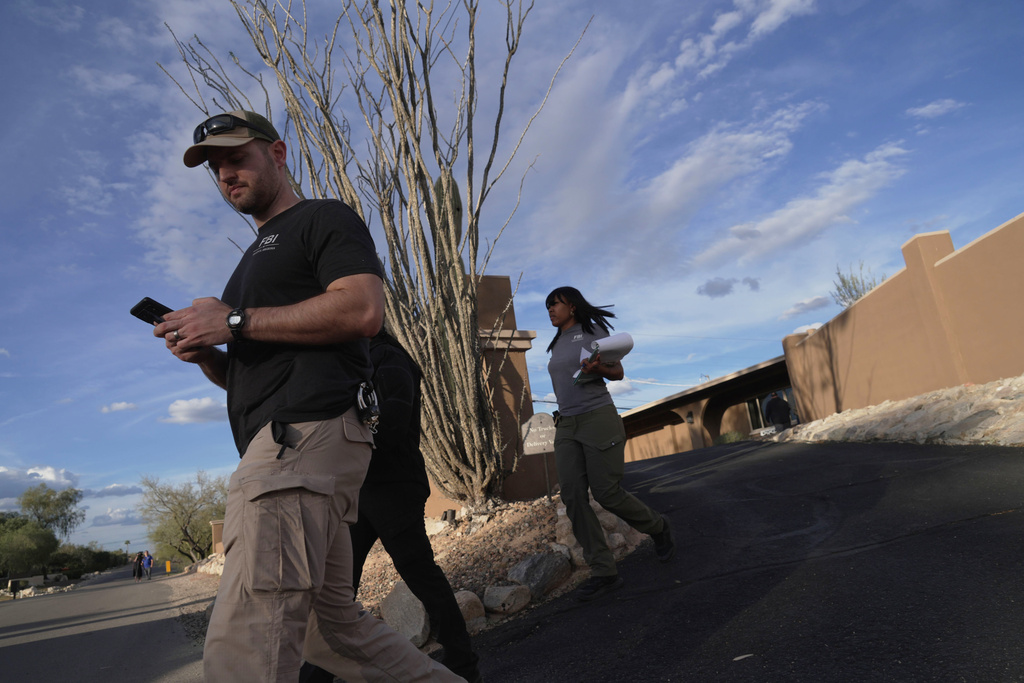 Law enforcement agents walk around the neighborhood where Annie Guthrie, whose mother Nancy Guthrie has been missing for more than a week, lives just outside Tucson, Ariz. (AP Photo/Ty ONeil)