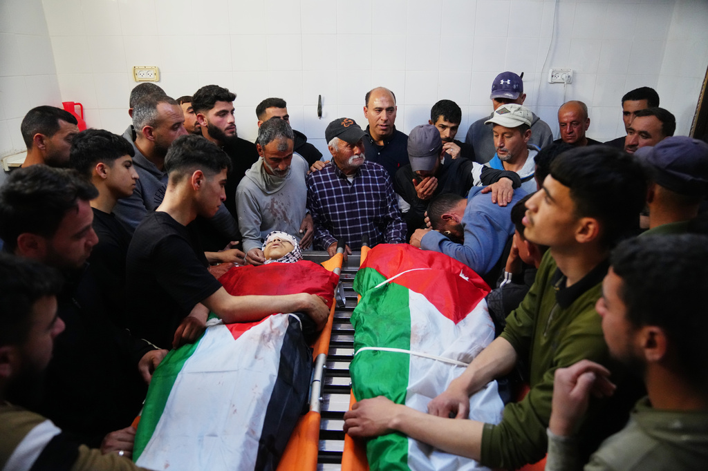 Mourners gather around the bodies of Aws al-Na'san and Jihad Abu Naim, residents of the West Bank village of al-Mughayyir, at the hospital's morgue in the West Bank city of Ramallah, Tuesday, April 21, 2026. (AP Photo/Mahmoud Illean)