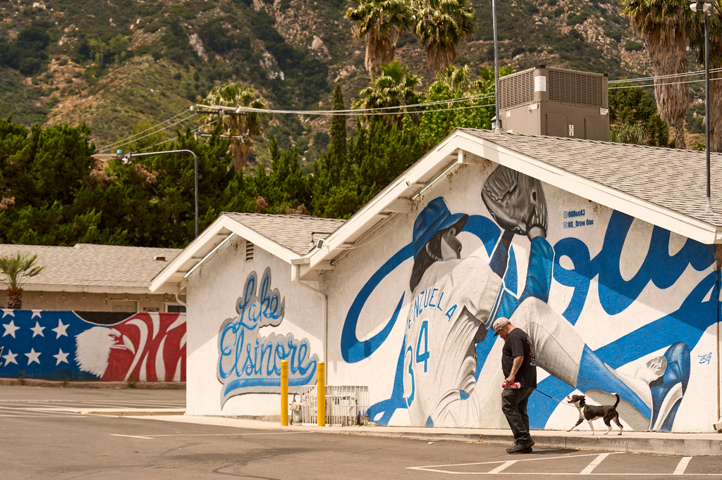 A man walks his dog past a liquor store in Lake Elsinore, Calif., on Tuesday, April 21, 2026. (AP Photo/Damian Dovarganes)