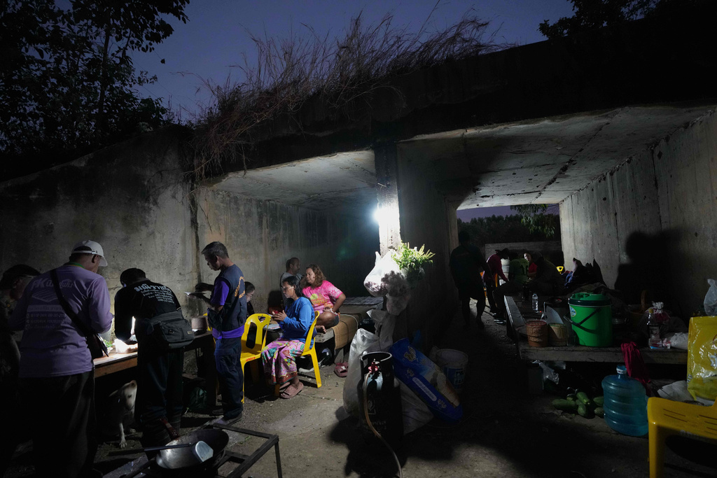 Thai residents cover in a shelter in Buriram province, Thailand, Thursday, Dec. 11, 2025. (AP Photo/Sakchai Lalit)