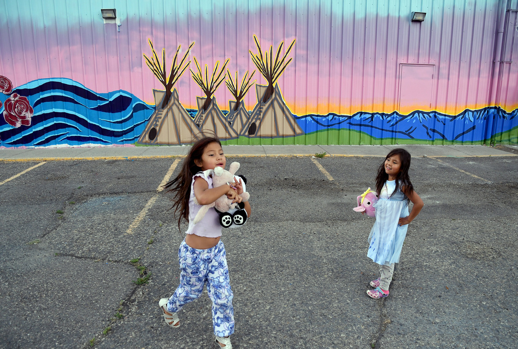 Jaelynn Duran, left, and Abigail Whiteman play in front of a mural at a gas station on the Wind River Reservation near Riverton, Wyo., on Saturday, Aug. 15, 2026. (AP Photo/Thomas Peipert)