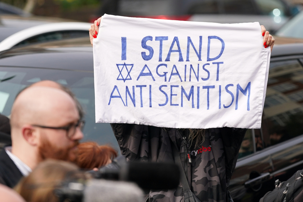 A protester shows a banner at Golders Green in London, Monday, March 23, 2026 after an apparent arson attack on four vehicles belonging to a Jewish ambulance service, Hatzola Northwest, in London.(AP Photo/Alberto Pezzali)