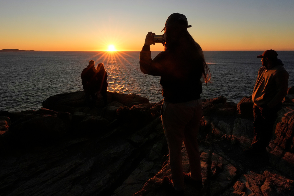 Michaela Zaidan, of Nashville, Tenn., photographs a couple at sunrise, Wednesday, Oct. 1, 2025, in Acadia National Park, Maine. (AP Photo/Robert F. Bukaty)
