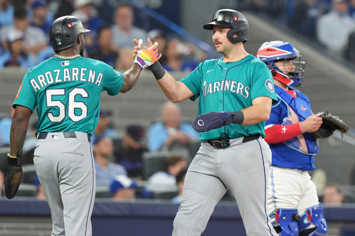 Seattle Mariners' Randy Arozarena (56) and Cal Raleigh, center, celebrate after scoring on a three-run home run by teammate Jorge Polanco during the fifth inning of Game 2 of baseball's American League Division Series against the Toronto Blue Jays in Toronto, Monday, Oct. 13, 2025. (Frank Gunn/The Canadian Press via AP) Seattle Mariners' Randy Arozarena (56) and Cal Raleigh, center, celebrate after scoring on a three-run home run by teammate Jorge Polanco during the fifth inning of Game 2 of baseball's American League Division Series against the Toronto Blue Jays in Toronto, Monday, Oct. 13, 2025. (Frank Gunn/The Canadian Press via AP)