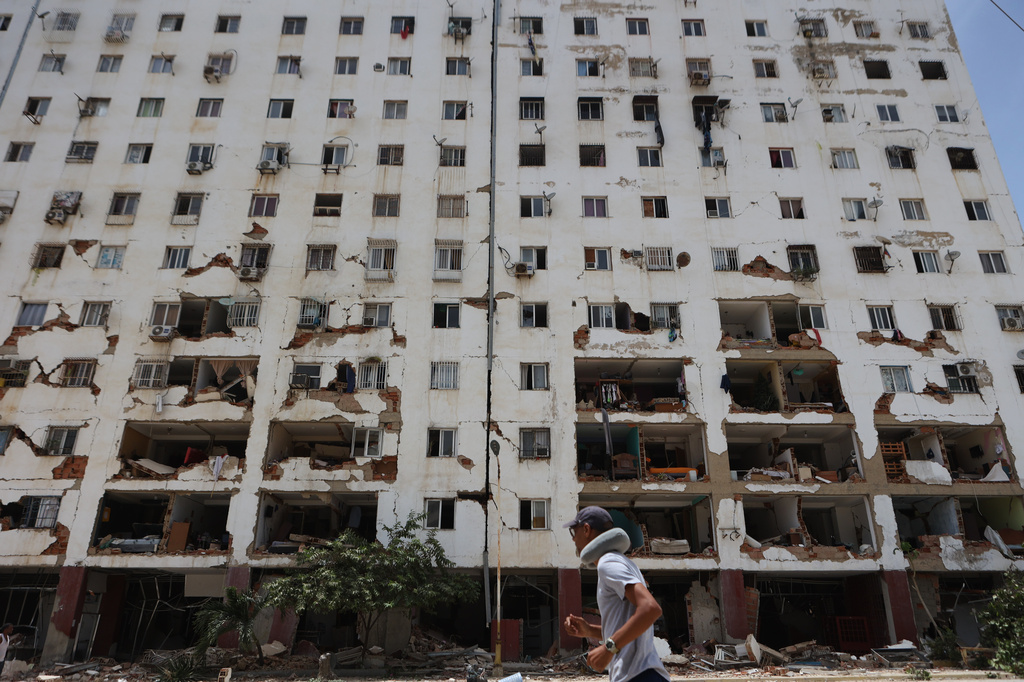 A resident walks past a damaged building a day after an earthquake and several aftershocks struck La Guaira, Venezuela, Thursday, June 25, 2026. (AP Photo/Pedro Mattey)