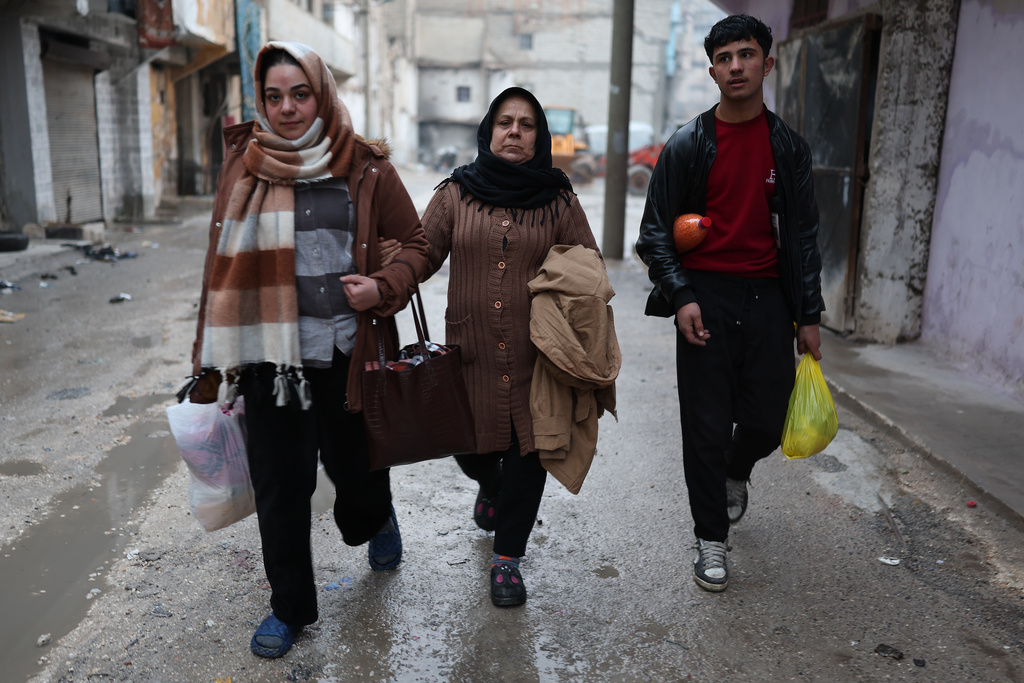 People flee the Sheikh Maqsoud neighborhood, where clashes between government forces and Kurdish fighters have been taking place in the northern city of Aleppo, Syria, Sunday, Jan. 11, 2026. (AP Photo/Ghaith Alsayed)