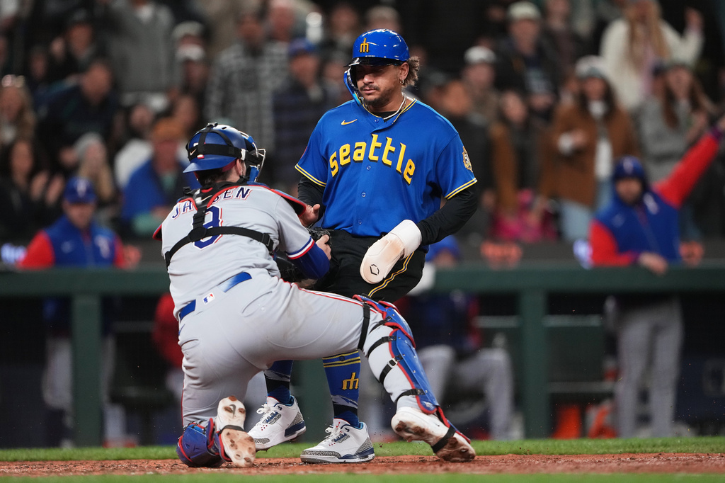 Seattle Mariners' Josh Naylor is tagged out at home by Texas Rangers catcher Danny Jansen trying to score on a single from Mariners' J.P. Crawford during the sixth inning of a baseball game, Friday, April 17, 2026, in Seattle. (AP Photo/Lindsey Wasson)