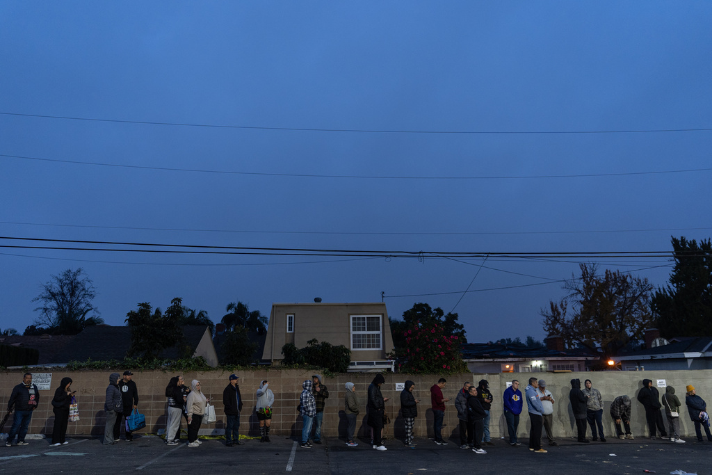 People wait in line to buy masa, a dough used to make tamales, outside Amapola Market in Downey, Calif., early Tuesday morning, Dec. 23, 2025. (AP Photo/Jae C. Hong)