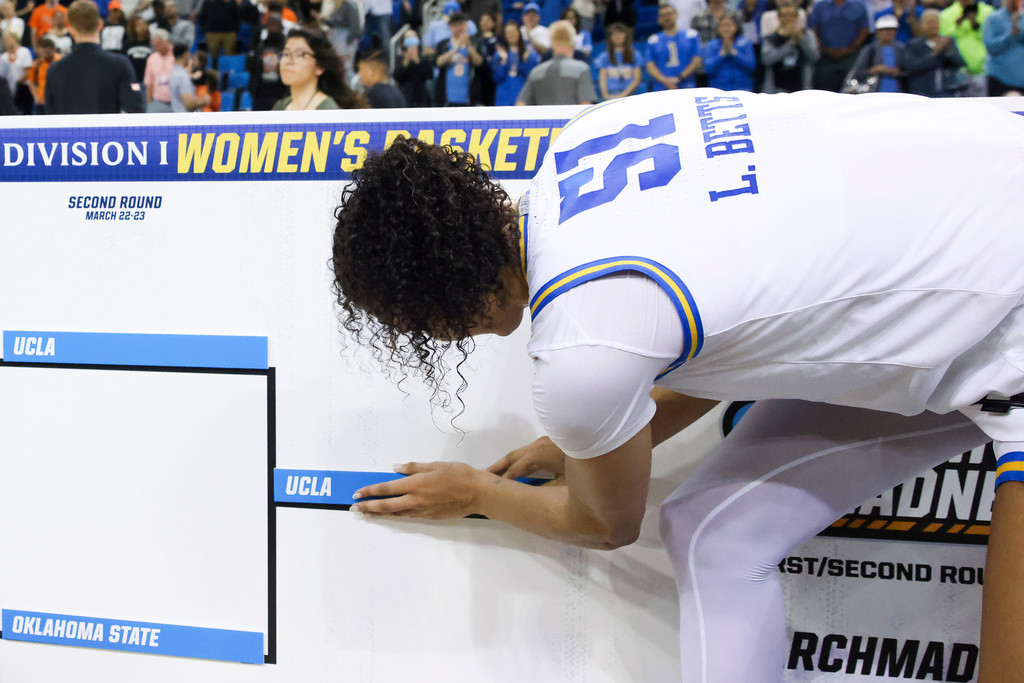 UCLA center Lauren Betts (51) places the UCLA bracket sticker on the board after UCLA defeats Oklahoma State in the second round of the NCAA college basketball tournament, Monday, March 23, 2026, in Los Angeles. (AP Photo/Jessie Alcheh)