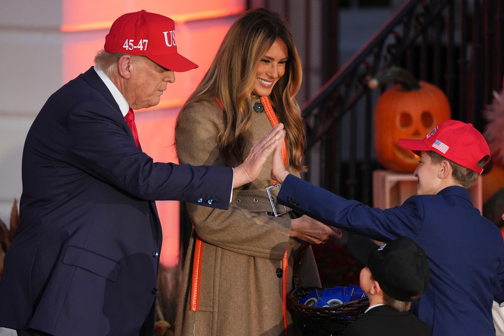 President Donald Trump, left, gives a high-five to a child dressed as him as first lady Melania Trump, center, look on during a Halloween event on the South Lawn of the White House, Thursday, Oct. 30, 2025, in Washington. (AP Photo/Jacquelyn Martin)