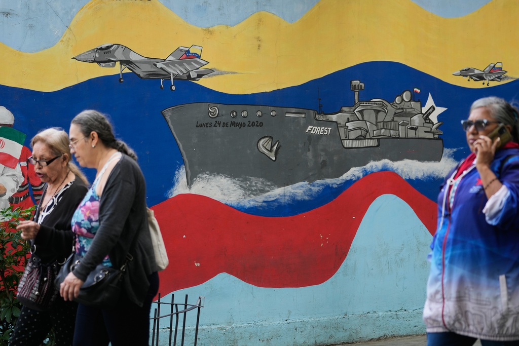 Pedestrians walk past a mural featuring a Venezuelan warship and aircraft in downtown Caracas, Venezuela, Tuesday, Nov. 11, 2025. (AP Photo/Ariana Cubillos)