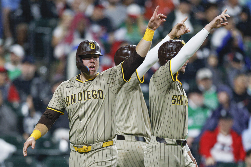 San Diego Padres designated hitter Gavin Sheets, left, celebrates with Jackson Merrill, right, and Manny Machado, center, after a double hit by Ryan O'Hearn against the Chicago White Sox during the sixth inning of a baseball game, Saturday, Sept. 20, 2025, in Chicago. (AP Photo/Kamil Krzaczynski)