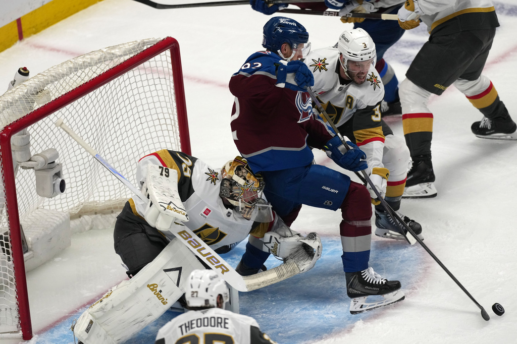 Vegas Golden Knights defenseman Brayden McNabb, back, struggles to control the puck as goaltender Carter Hart, front, runs into Colorado Avalanche left wing Gabriel Landeskog during the first period in Game 1 of the Western Conference finals NHL hockey Stanley Cup playoff series Wednesday, May 20, 2026, in Denver. (AP Photo/David Zalubowski)