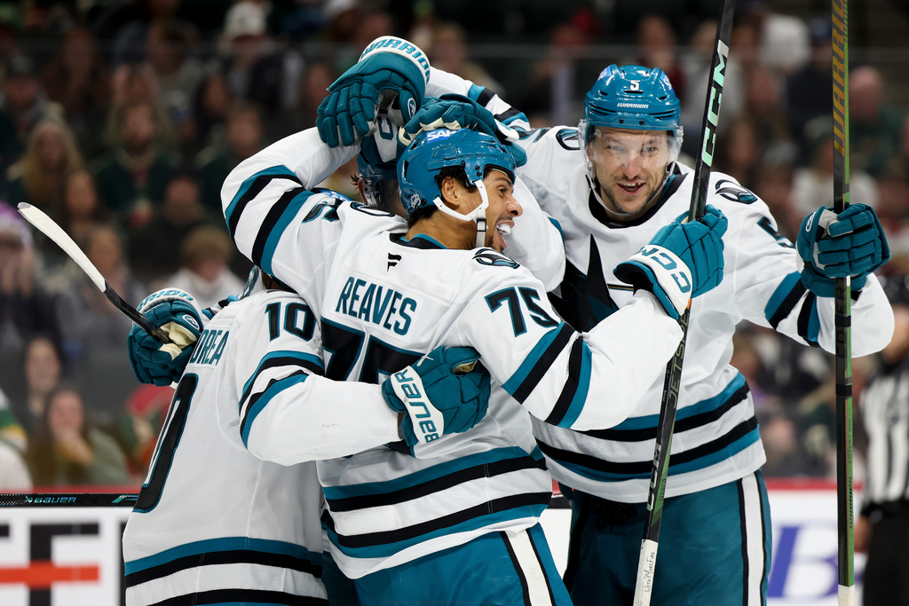 San Jose Sharks right wing Ryan Reaves (75) celebrates with center Ty Dellandrea (10) and defenseman Vincent Desharnais (5) after scoring during the second period of an NHL hockey game against the Minnesota Wild, Sunday, Oct. 26, 2025, in St. Paul, Minn. (AP Photo/Ellen Schmidt)