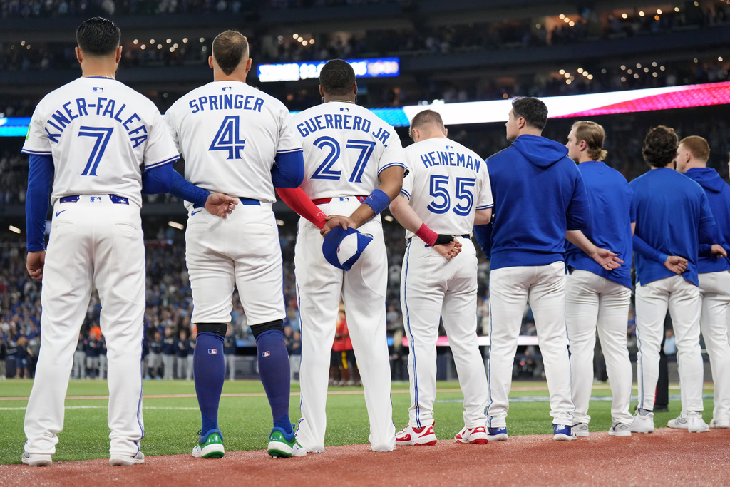 Toronto Blue Jays' Isiah Kiner-Falefa (7), George Springer (4), Vladimir Guerrero Jr. (27), Tyler Heineman (55) and members of the bullpen line up for the singing of the national anthems ahead of Game 7 of baseball's American League Championship Series against the Seattle Mariners in Toronto, Monday, Oct. 20, 2025. (Nathan Denette/The Canadian Press via AP)