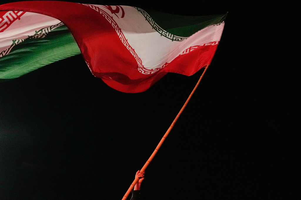 A man waves an Iranian flag during a pro-government gathering at a square in Tehran, Iran, Tuesday, Aug. 11, 2026. (AP Photo/Vahid Salemi)
