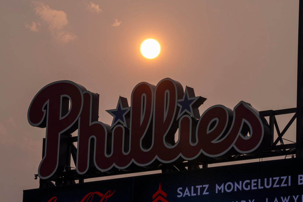 The Sun has an orange cast from smoke coming down from the Canadian wildfires as it sets near the Philadelphia Phillies scoreboard during the fourth inning of a baseball game against the New York Mets, Thursday, July 16, 2026, in Philadelphia. (AP Photo/Chris Szagola)