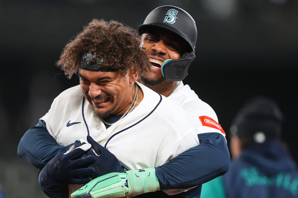 Seattle Mariners' Josh Naylor, front, is hugged by Julio Rodríguez, back, as they celebrate Naylor's game-winning single against the Athletics during the ninth inning of a baseball game, Wednesday, April 22, 2026, in Seattle. (AP Photo/Lindsey Wasson)